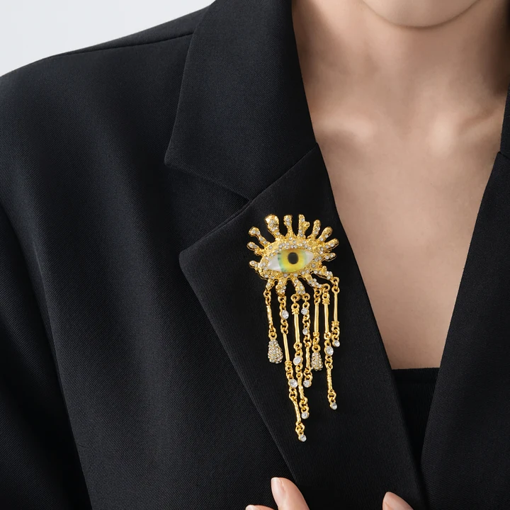 Eye brooch with chains shown in worn / black tailoring